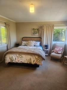 a bedroom with a bed and a chair and windows at Holden's Hideaway MBT in Rotorua