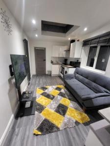 uma sala de estar com um sofá e um tapete em Fuzzys place em Londres