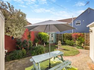 a picnic table with an umbrella in a garden at Curlew Cottage in Caister-on-Sea