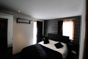 a bedroom with a black and white bed with a window at Chalet Des Domaines De La Vanoise - Pièces 134 in Peisey-Nancroix
