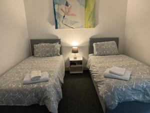 two beds in a small room with towels on them at 140 MAIN ST GROUND LEFT in Largs