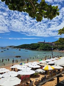 a beach with many umbrellas and people in the water at Casa do sossego in Cabo Frio