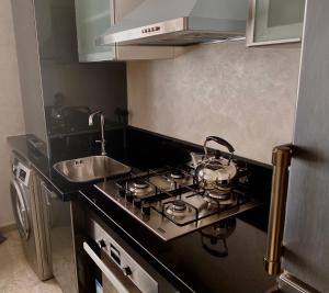 uma cozinha com uma placa de fogão e um lavatório em Appartement près de Novotel face au parc em Mohammedia