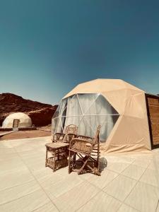 two chairs and a table in front of a tent at Katrina Rum camp in Wadi Rum