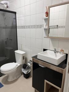 a bathroom with a toilet and a sink and a mirror at Apartamento Centro Ametista do Sul in Ametista do Sul