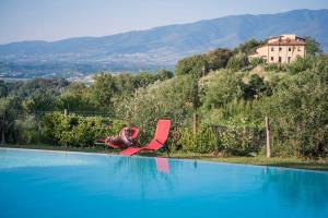 uma cadeira vermelha sentada ao lado de uma piscina em Appartement in Figline Valdarno mit Terrasse, Grill und Garten em Figline Valdarno