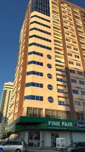 un edificio alto con coches estacionados frente a él en Place where stay for good time, en Ajman