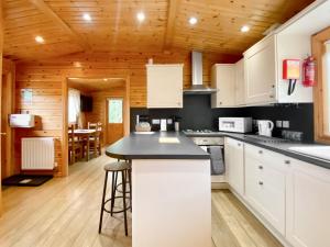 cocina con armarios blancos y encimera negra en Magnolia Lodge-uk46280, en Camerton