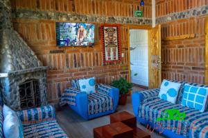 a living room with two blue chairs and a tv at Watzara Wasi Cottage Familiar Camprestre Y Lofts en Cotacachi in Cotacachi