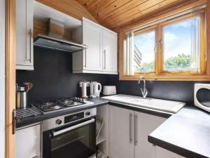 een keuken met witte kasten, een fornuis en een wastafel bij Maple - Uk46284 in Camerton
