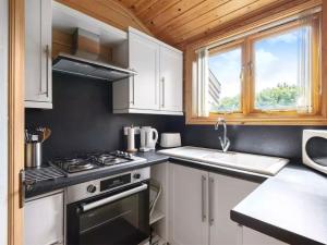 a kitchen with white cabinets and a stove and a sink at Maple - Uk46284 in Camerton