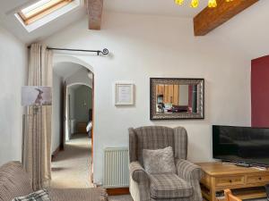 a living room with two chairs and a tv at Clematis Cottage in Elton