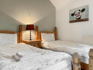 a bedroom with two beds and a picture of a cow on the wall at Clematis Cottage in Elton