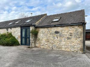 a stone building with a roof and windows on it at Clematis Cottage in Elton