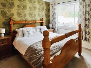 a bedroom with a wooden bed and a window at Torr Caladh in Glenfinnan
