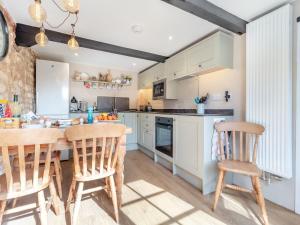 a kitchen with white cabinets and a wooden table and chairs at Rose Cottage - Ukc4238 in Great Snoring