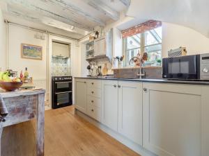 a large kitchen with white cabinets and a window at Vine Cottage - Ukc4237 in Great Snoring