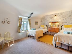 a bedroom with two beds and a table and a window at Cherry Tree Cottage - Uk30237 in Great Snoring
