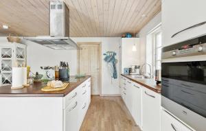 a kitchen with white cabinets and a black appliance at Awesome Home In Gilleleje With Kitchen in Gilleleje +18 photos