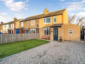 uma casa de tijolos com uma cerca e um quintal em Snowdrop Cottage em Seahouses