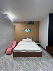 a bedroom with a large bed and a pink chair at Thành Phố Mới Hotel in Ðịnh Hòa