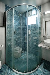 a glass shower in a bathroom with a sink at Palm Regal Resort in Gopālpur