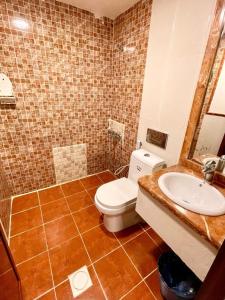 un baño con inodoro y lavabo en مرفق ضيافة خاص - شقة عائلية, en Al Fayşalīyah
