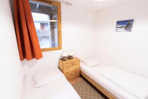 Habitación pequeña con 2 camas y ventana en Les Chalets Petit Bonheur - Chalets pour 6 Personnes 474, en Villarodin-Bourget