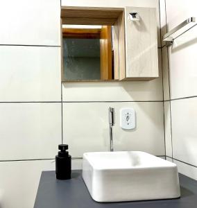 a bathroom with a white sink and a mirror at CHARMOSO E BEM LOCALIZADO in Maracaju