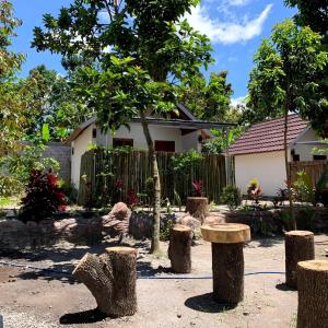 a garden with tree stumps in front of a house at Avocado homestay in Tetebatu