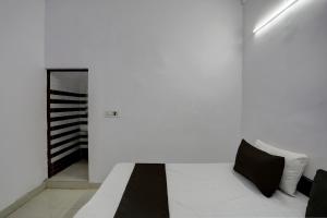 biały pokój z łóżkiem z czarnymi poduszkami w obiekcie OYO HOTEL KAVYA RESIDENCY w mieście Aligarh