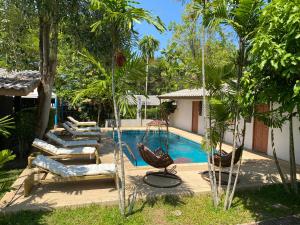 a swimming pool with a swing and chairs and trees at Apollo Hotel Chalong in Ban Suan