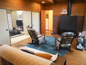 - un salon avec un canapé, des chaises et une télévision dans l'établissement ～みらい荘～　天然温泉付き一日一組様限定の６４坪広々民泊別荘, à Kirishima