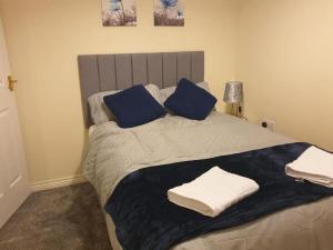 a bedroom with a large bed with blue pillows at Oasis Abode @ Ashover Newcastle in Kenton