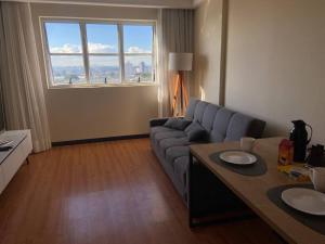 a living room with a couch and a table at Flat 1 qto, piscina, loc central in São José dos Pinhais
