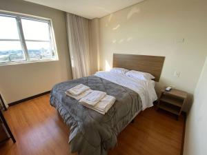 a bedroom with a bed with two towels on it at Flat 1 qto, piscina, loc central in São José dos Pinhais