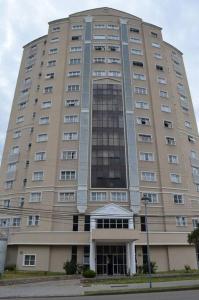 a large tan building with a lot of windows at Flat 1 qto, piscina, loc central in São José dos Pinhais
