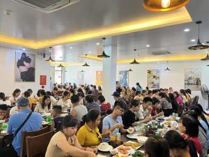 a large group of people sitting at tables eating food at Khách Sạn Moonlight FLC Sầm Sơn in Sầm Sơn