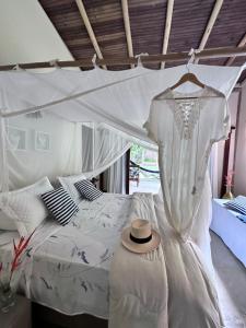 um vestido de noiva pendurado numa cama num quarto em Refugio Trancoso suite Mare em Trancoso