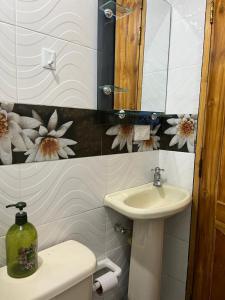 baño con lavabo y aseo con flores en la pared en Pacifica Hostel en Medellín