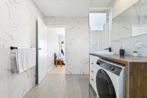 a white kitchen with a washing machine in it at Paradise Retreat - relax & escape in Potato Point