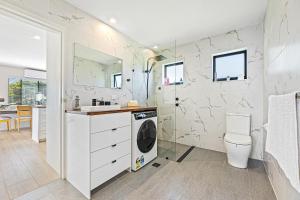 a white bathroom with a washer and dryer in it at Paradise Retreat - relax & escape in Potato Point