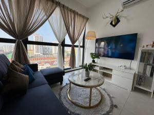 a living room with a couch and a table and a large window at DeLuma-Urban Suites in Jelutong