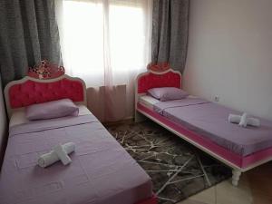 two beds in a room with pink beds with crowns at Layla Home in Alexandroupoli