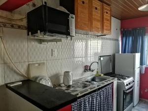 eine kleine Küche mit einer Spüle und einer Mikrowelle in der Unterkunft Casita céntrica in Trinidad