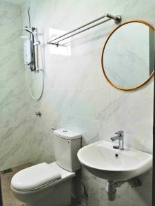 La salle de bains est pourvue de toilettes, d'un lavabo et d'un miroir. dans l'établissement Bayu Temiang Seremban- Your Urban Retreat, à Seremban