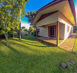 a small white house with a grass yard at Quarto Aconchegante na - Peniel Guesthouse in Gramado