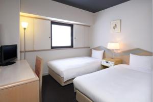 a hotel room with two beds and a television at HOTEL MYSTAYS Miyazaki in Miyazaki