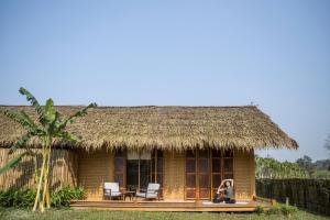 Eine Frau, die auf der Veranda einer Hütte sitzt. in der Unterkunft Alba Wellness Resort By Fusion in Hue