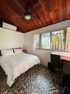 a bedroom with a bed and a desk and windows at Casa Verde in Uvita